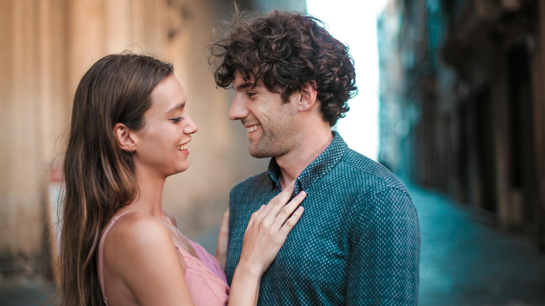 A happy young couple embracing and smiling while enjoying a romantic moment outdoors.